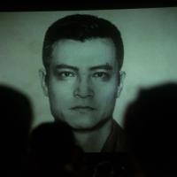 Headshot of an angry looking man in between the shadows of two figures.