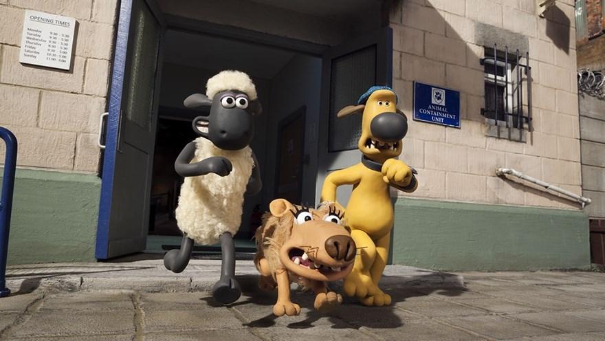 Three animated characters from the "Shaun the Sheep" series, Shaun the Sheep, Bitzer the dog, and a third mischievous animal, exit a building labeled "Animal Containment Unit" with listed opening times.